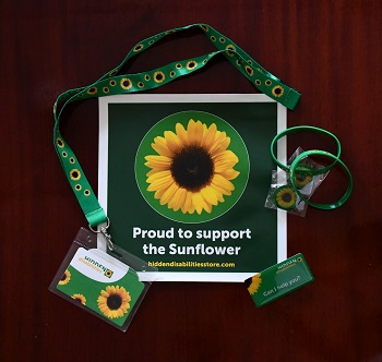 Poster with 'proud to support the Sunflower' with broches bracelets and lanyards with sunflowers and the hidden disabilities card