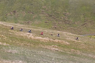Aerial shot of 7 bikers riding illegally on open field