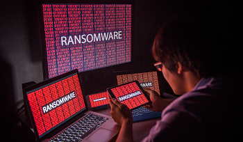 Person looking at multiple devices' screen with 'ransomware' written on them