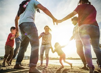 Family holding hands in circle and dancing at the beach