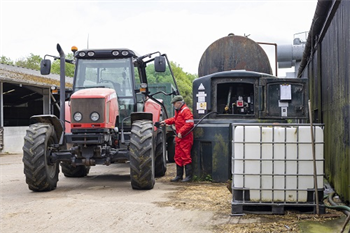 Man filling up farm tractor with red diesel