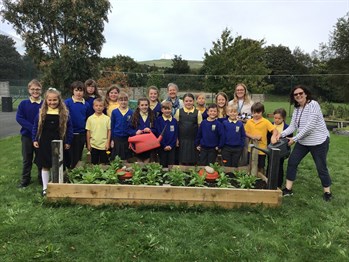 Group of students from St John’s primary school standing behind a vegetable garden that they are growing as a way to make the school more eco friendly, as part of the seven-step programme for the green flag