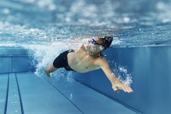 Male mid swimming stroke in pool